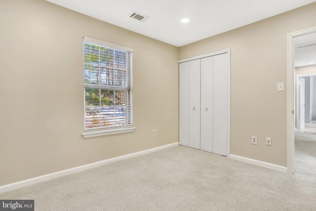 unfurnished bedroom featuring light carpet and a closet