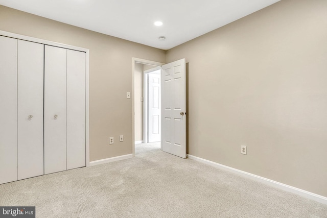 unfurnished bedroom with a closet and light carpet