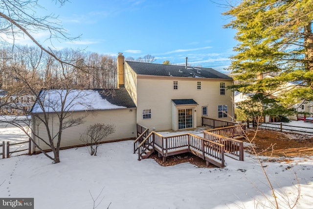 snow covered back of property featuring a deck