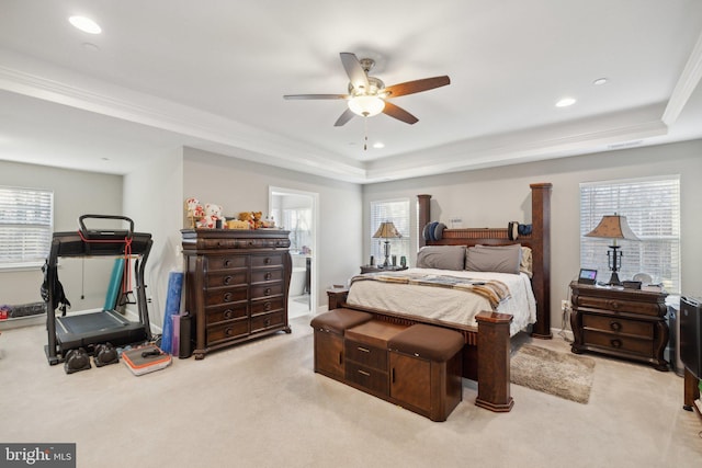 bedroom featuring multiple windows, a raised ceiling, light carpet, and ensuite bathroom