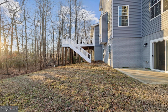 view of home's exterior featuring a wooden deck, a patio area, and a lawn