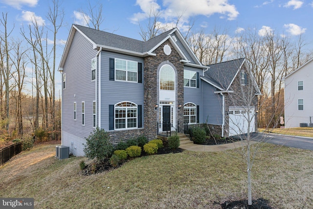 view of front of property with cooling unit, a garage, and a front lawn