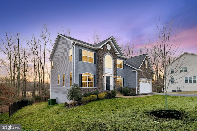 view of front of home featuring a garage, a yard, and central AC