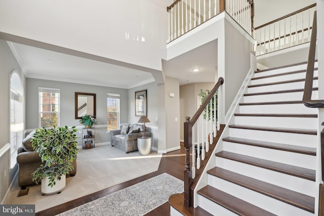 entryway featuring crown molding, a towering ceiling, and hardwood / wood-style flooring