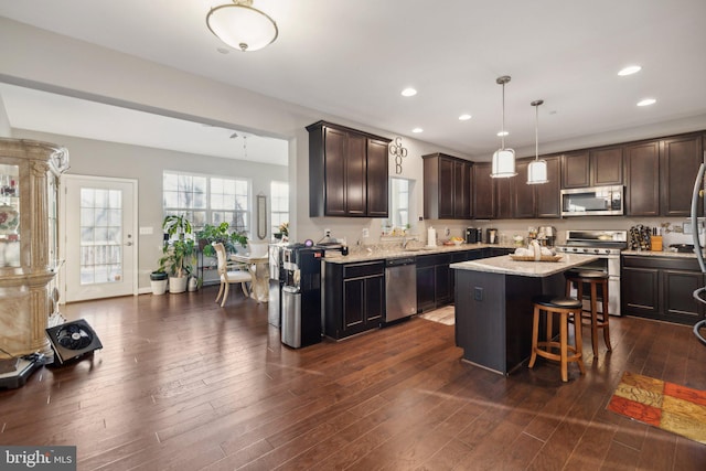 kitchen featuring a kitchen island, pendant lighting, a kitchen breakfast bar, dark brown cabinetry, and stainless steel appliances