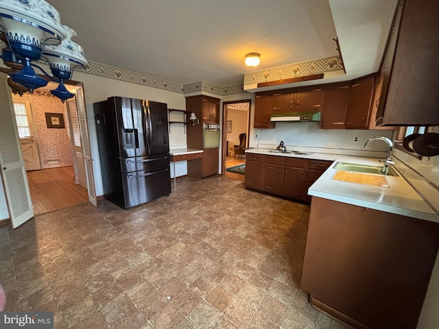 kitchen featuring black fridge with ice dispenser, sink, and cooktop