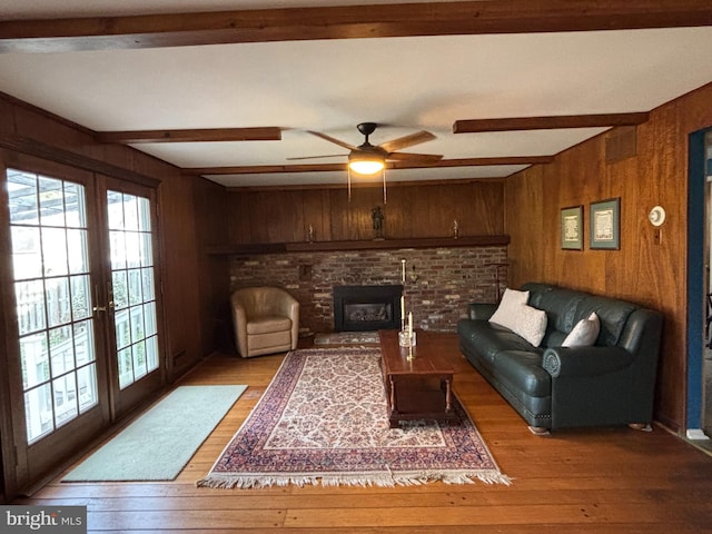 living room with french doors, beam ceiling, and wooden walls