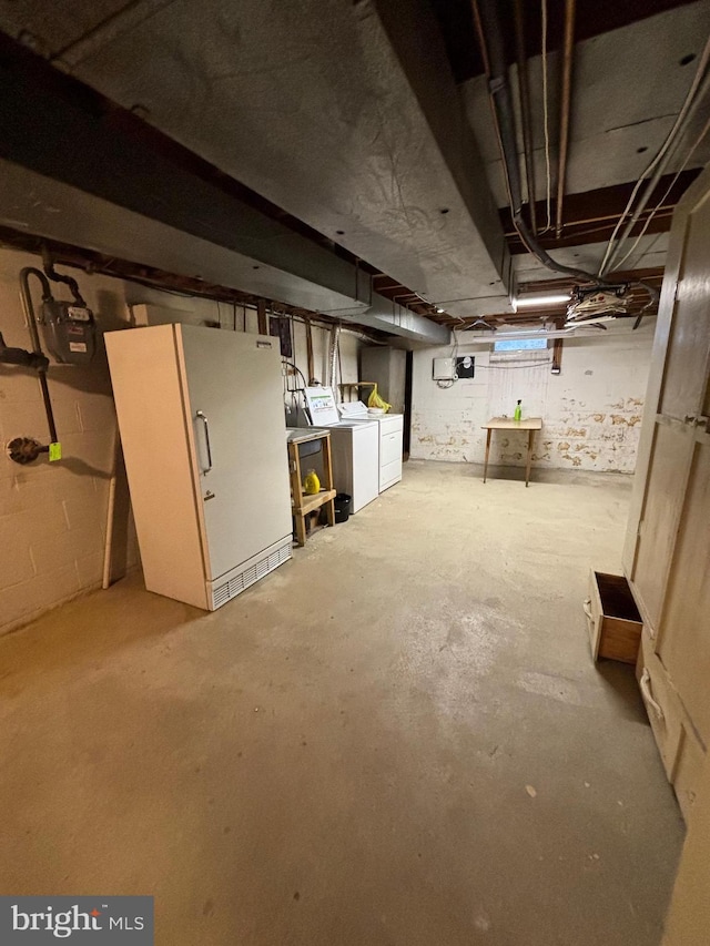 basement with washer and dryer and white fridge