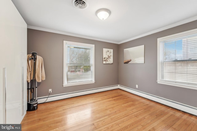 empty room with ornamental molding, light hardwood / wood-style floors, and baseboard heating