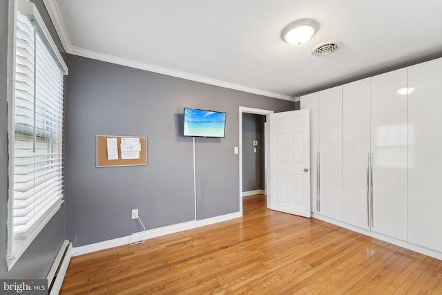 unfurnished bedroom featuring crown molding, baseboard heating, and light hardwood / wood-style flooring