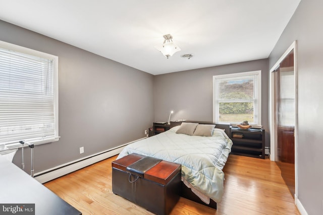 bedroom with light hardwood / wood-style flooring and baseboard heating