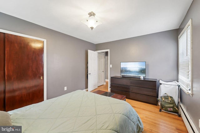 bedroom with multiple windows, a baseboard radiator, and light hardwood / wood-style flooring