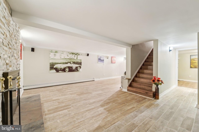 basement with baseboard heating and light hardwood / wood-style flooring