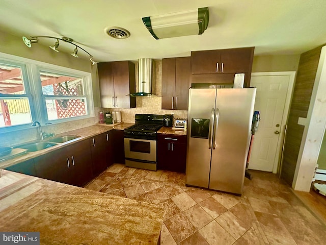 kitchen with stainless steel appliances, dark brown cabinets, sink, and wall chimney exhaust hood