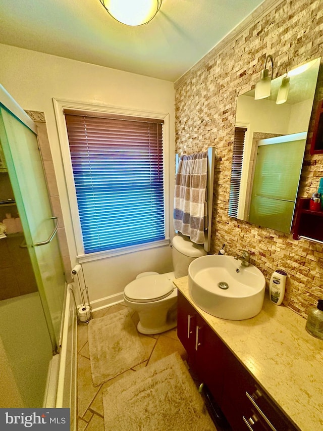 bathroom featuring tile patterned flooring, vanity, toilet, and walk in shower