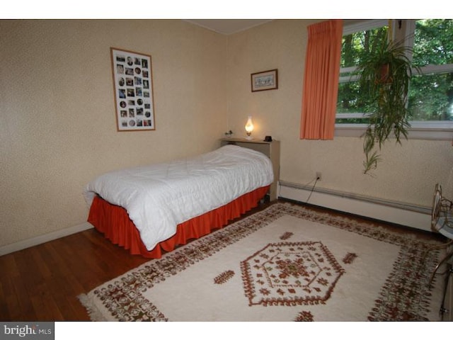 bedroom featuring hardwood / wood-style flooring and a baseboard heating unit