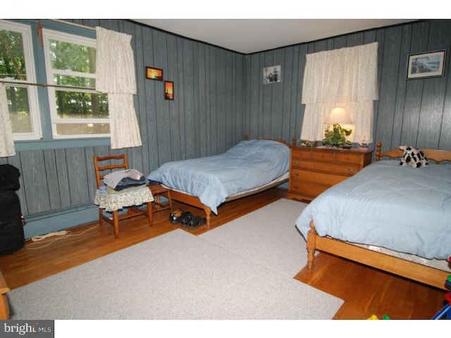 bedroom with wood-type flooring and wooden walls