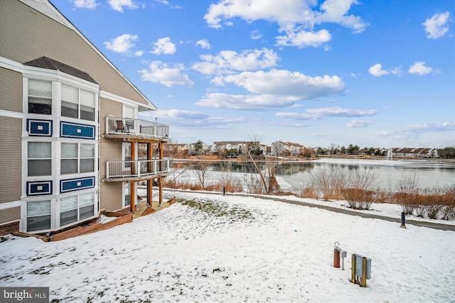 snowy yard featuring a balcony and a water view