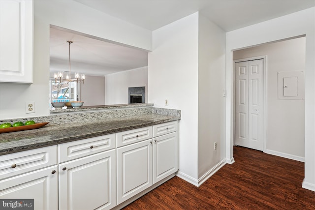 kitchen with white cabinetry, pendant lighting, dark stone counters, and a notable chandelier