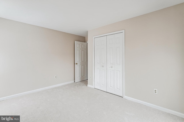 unfurnished bedroom featuring light colored carpet and a closet