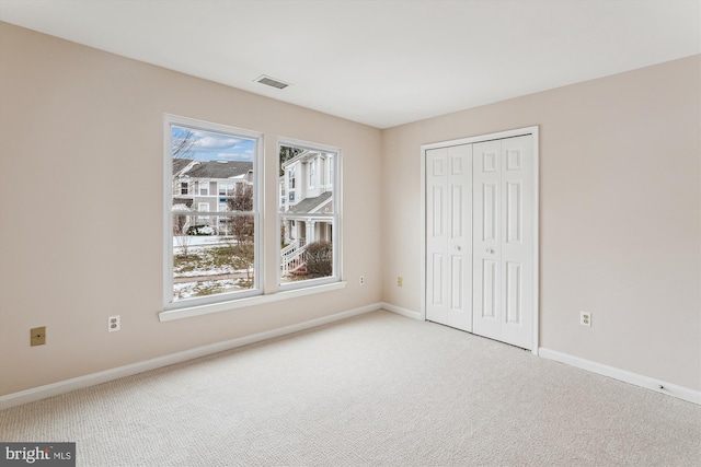 unfurnished bedroom with multiple windows, a closet, and light carpet