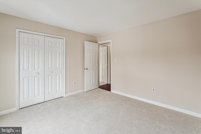 unfurnished bedroom featuring light carpet and a closet