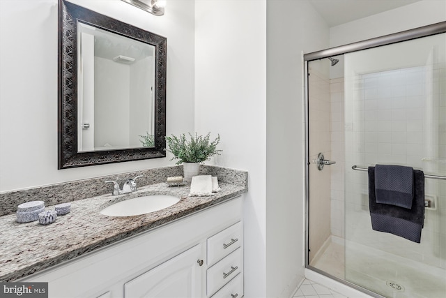 bathroom with a shower with shower door, vanity, and tile patterned flooring