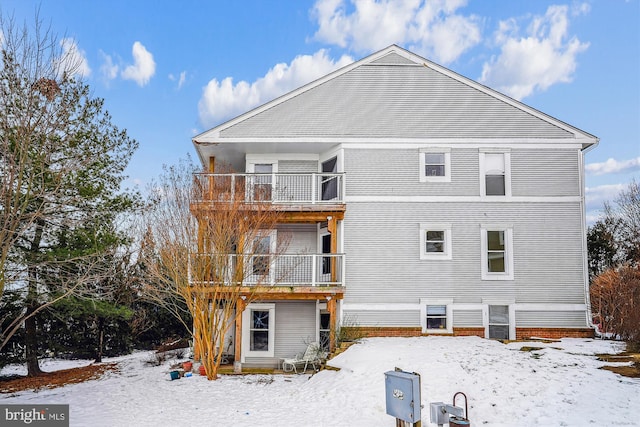 snow covered back of property with a balcony