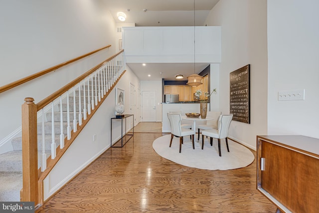 dining room with a towering ceiling and wood-type flooring