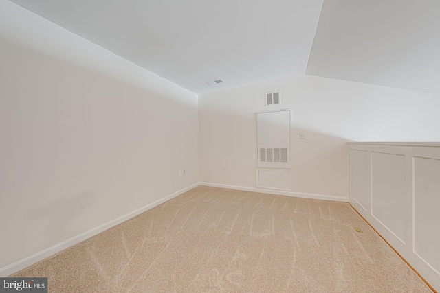 spare room featuring lofted ceiling and light carpet