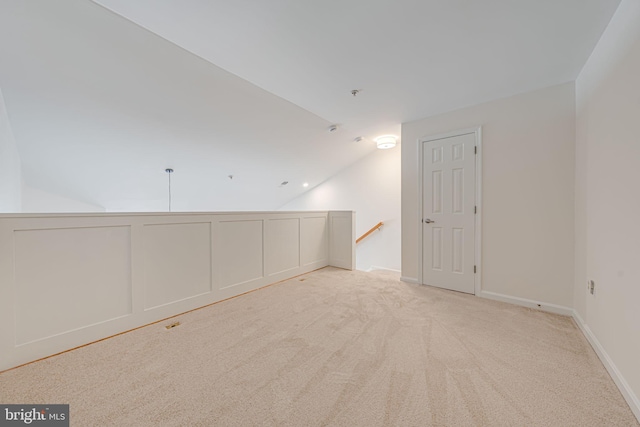 carpeted spare room featuring vaulted ceiling