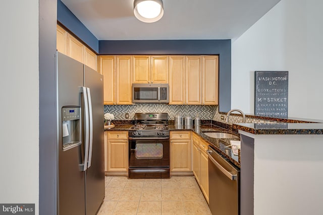 kitchen featuring stainless steel appliances, kitchen peninsula, sink, and dark stone countertops