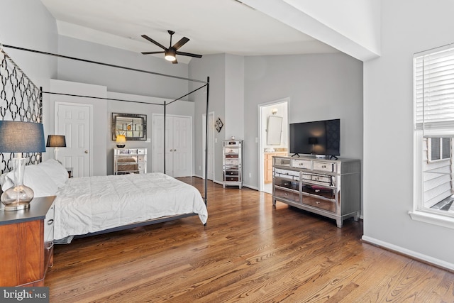 bedroom featuring ceiling fan, multiple windows, lofted ceiling, and hardwood / wood-style floors