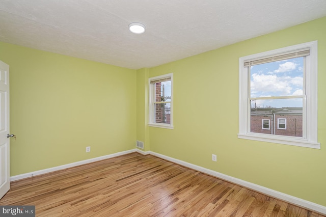 spare room with a textured ceiling and light hardwood / wood-style floors