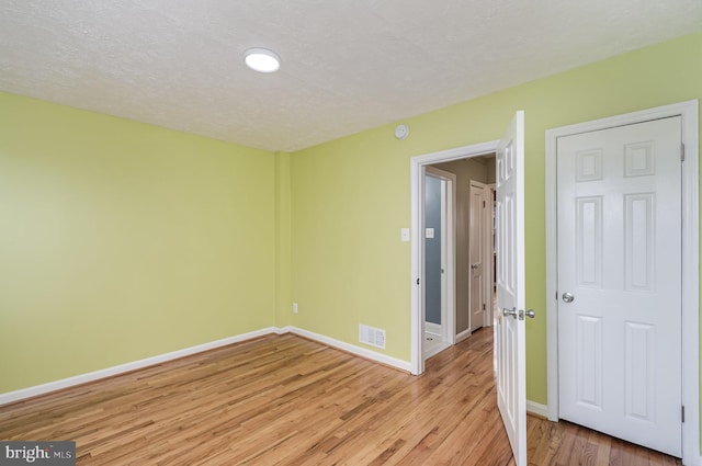 spare room featuring a textured ceiling and light hardwood / wood-style flooring