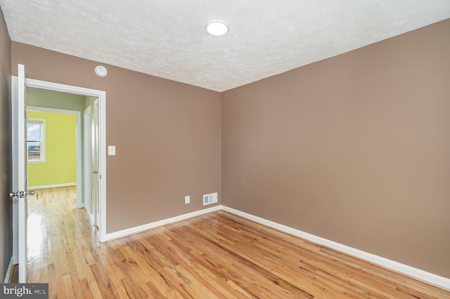 unfurnished room featuring a textured ceiling and light hardwood / wood-style flooring