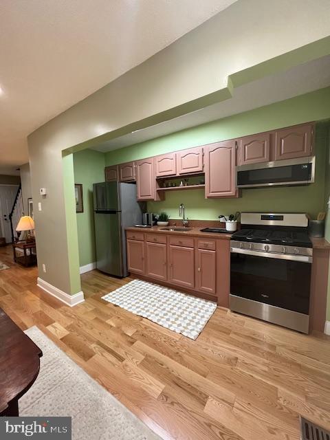 kitchen with appliances with stainless steel finishes, light hardwood / wood-style floors, and sink