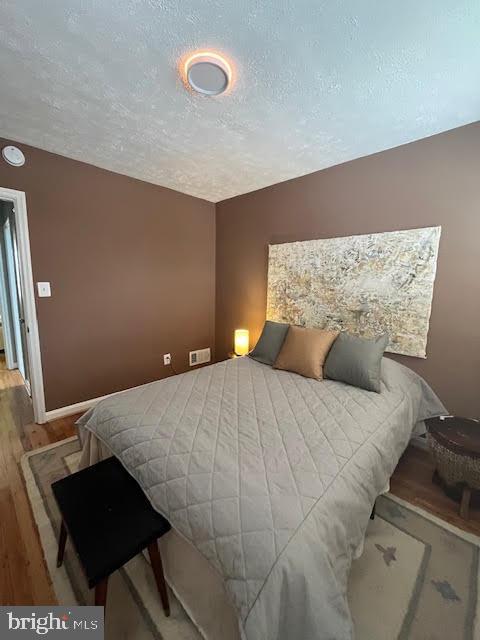 bedroom with a textured ceiling and hardwood / wood-style floors