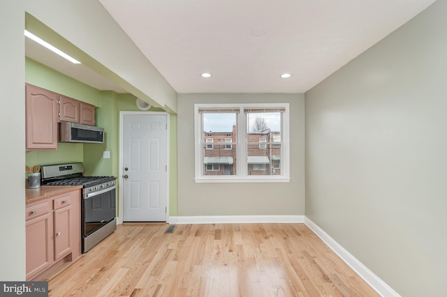 kitchen with light hardwood / wood-style floors and appliances with stainless steel finishes