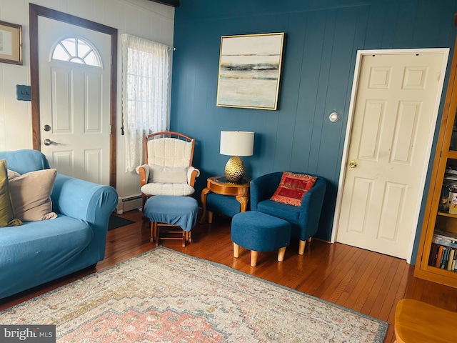 sitting room with hardwood / wood-style floors, wooden walls, and a baseboard radiator