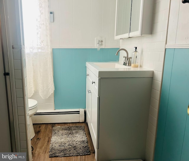 bathroom featuring toilet, a baseboard heating unit, hardwood / wood-style flooring, and vanity