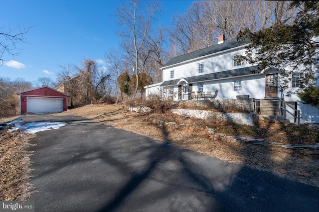 snow covered property featuring a garage and an outdoor structure