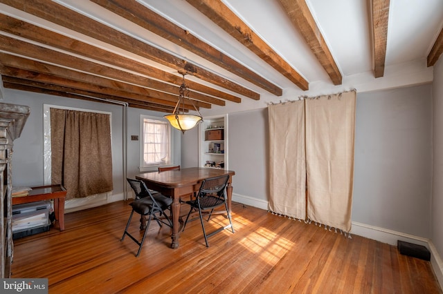 dining space featuring wood-type flooring and beamed ceiling