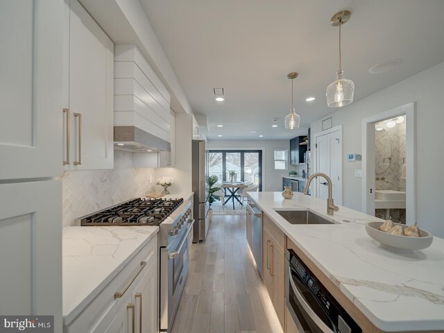 kitchen with white cabinetry, sink, stainless steel appliances, and light stone countertops