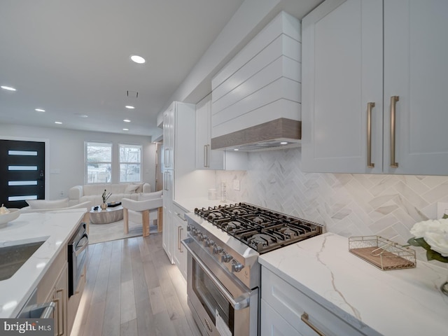 kitchen with stainless steel range, light stone countertops, custom exhaust hood, and white cabinets