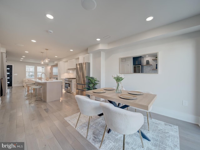 dining space with sink and light wood-type flooring