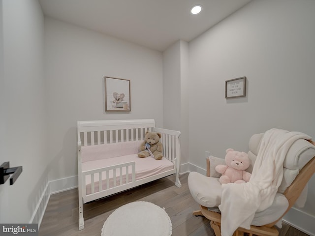 bedroom with a nursery area and hardwood / wood-style flooring