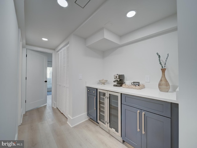 bar with beverage cooler and light wood-type flooring