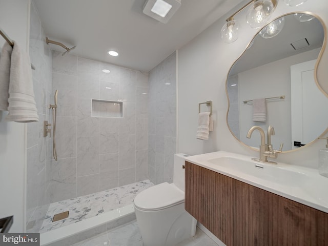 bathroom featuring vanity, toilet, and a tile shower