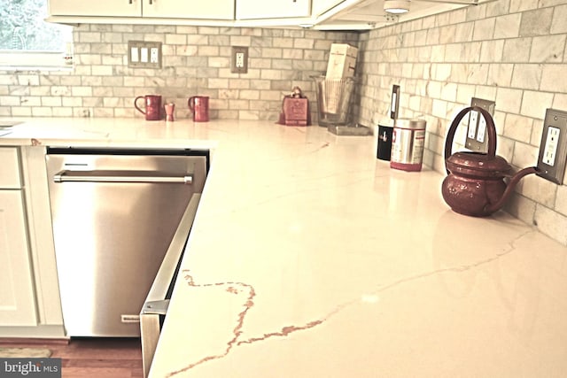 kitchen featuring stainless steel dishwasher and light stone countertops